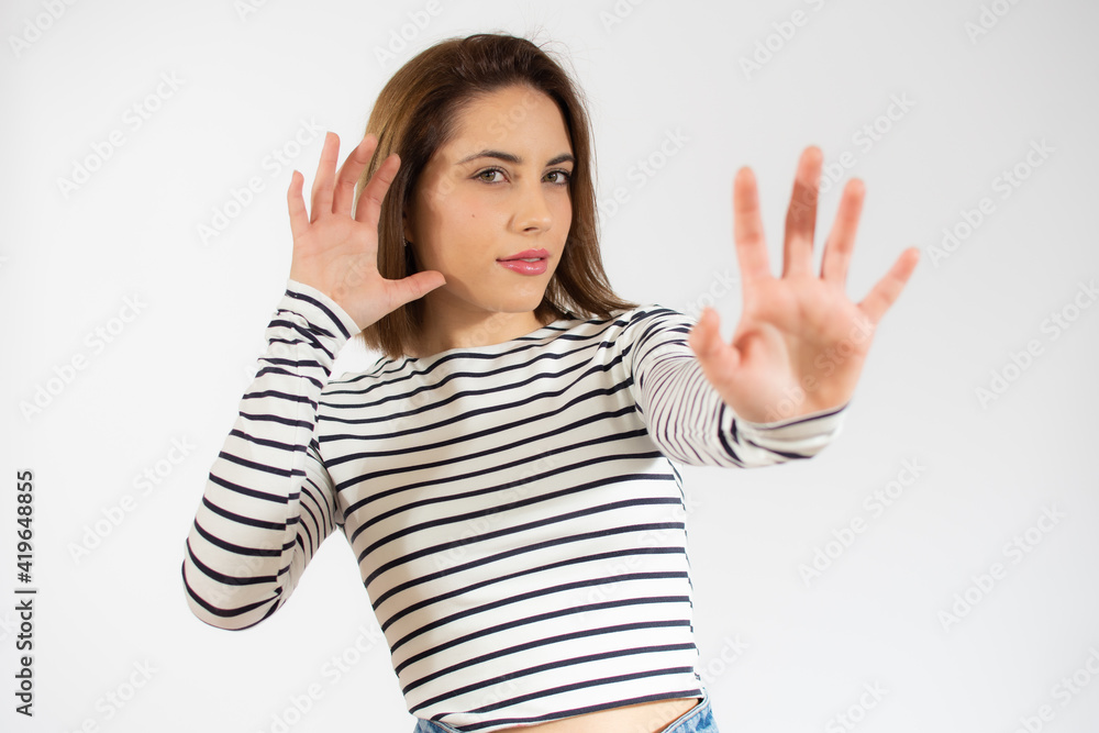 Young beautiful woman wearing casual striped t-shirt over isolated white background Moving away hands palms showing refusal and denial with afraid and disgusting expression. Stop and forbidden. Young beautiful woman wearing casual striped t-shirt over isolated white background Moving away hands palms showing refusal and denial with afraid and disgusting expression. Stop and forbidden.