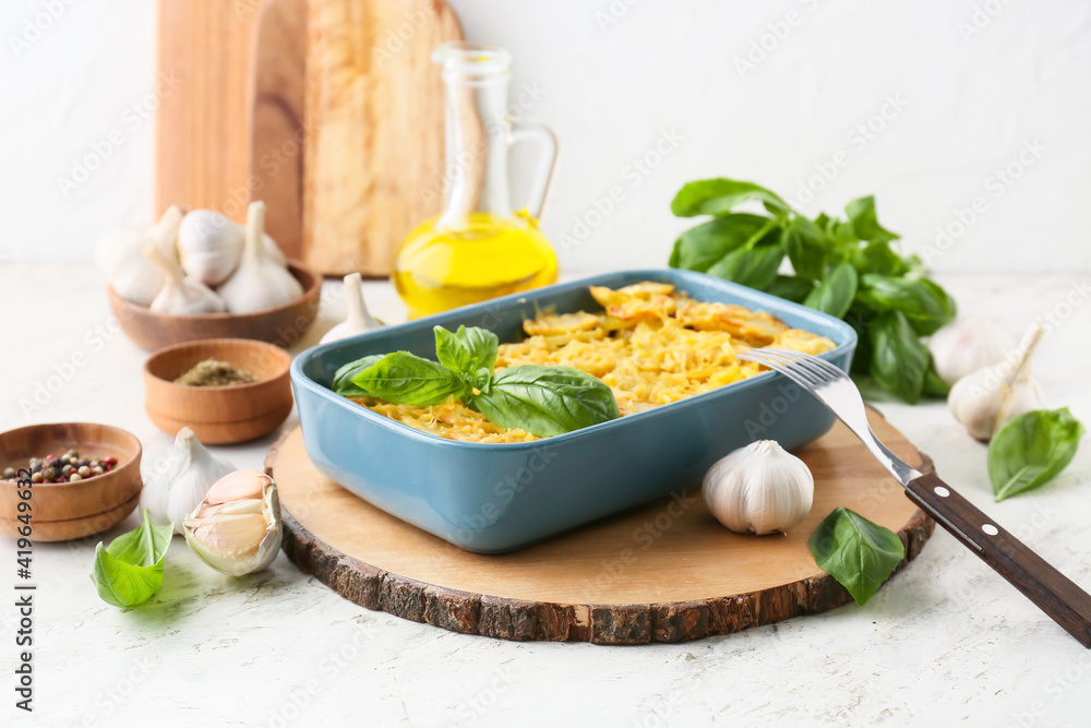 Baking dish of tasty potato with garlic on light background Baking dish of tasty potato with garlic on light background