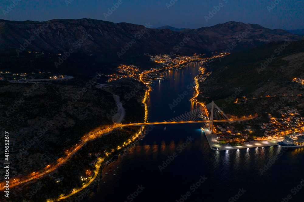 Aerial drone shot of Port Gruz by Dubrovnik bridge with lights in Croatia summer at dusk