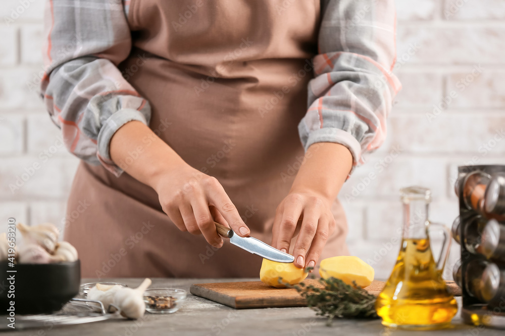 Woman cutting potatoes in kitchen