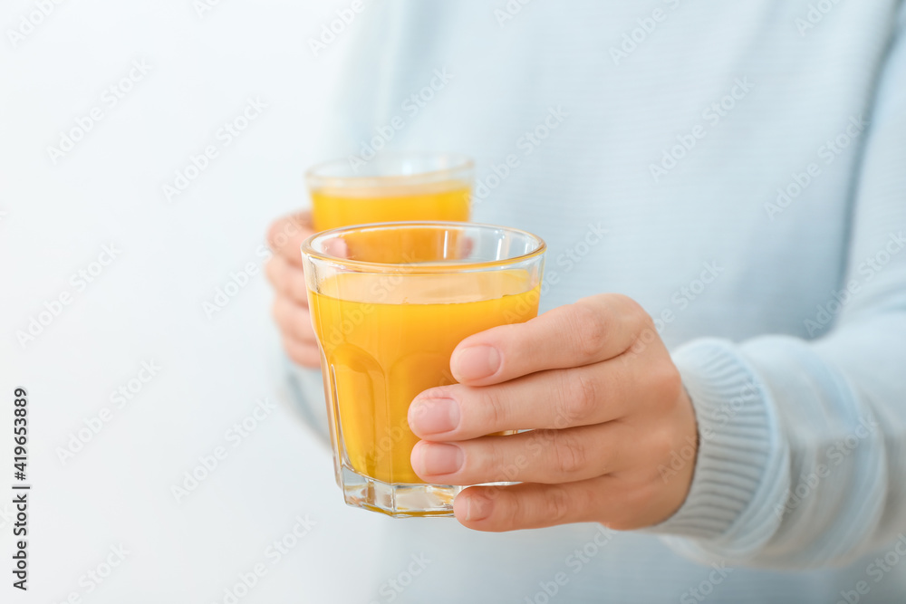 Woman with glasses of healthy turmeric drink on light background Woman with glasses of healthy turmeric drink on light background