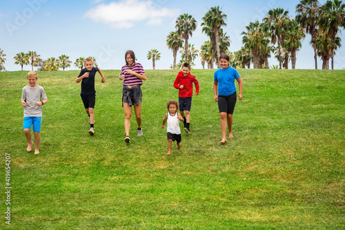 Large diverse group of active children running together in an outdoor park. Boys and girls of different ages having fun playing together outdoors
