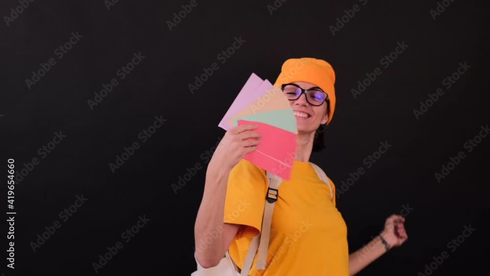 Young positive hipster student woman with colorful letters and backpack on black background happy dancing Young positive hipster student woman with colorful letters and backpack on black background happy dancing