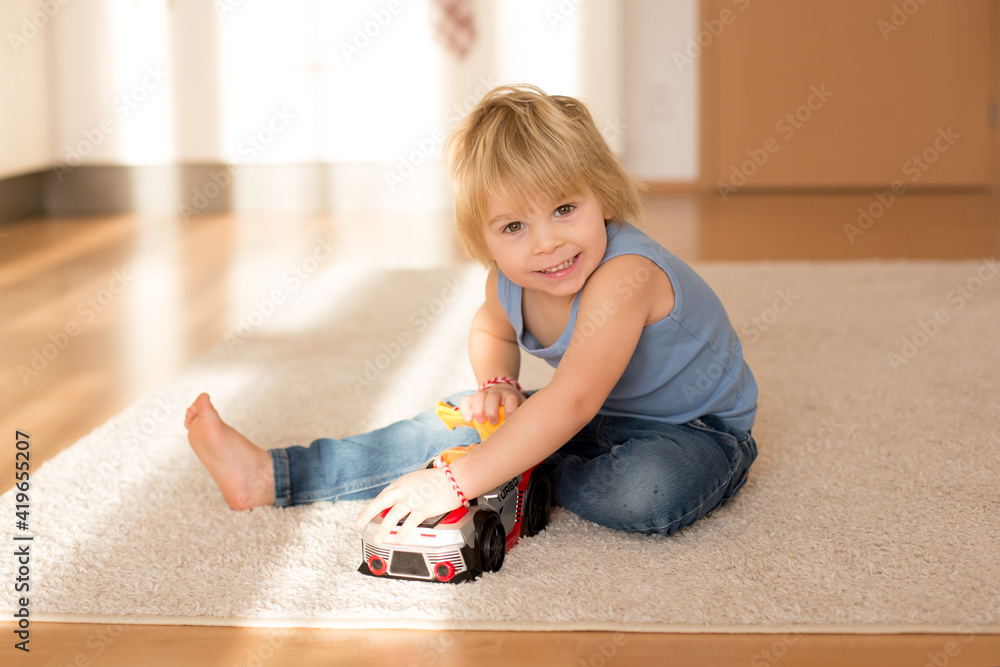 Cute blond toddler child, playing with big toy car Cute blond toddler child, playing with big toy car