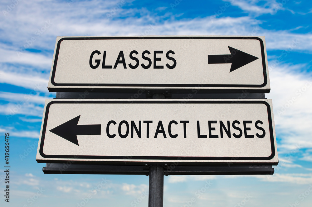 Glasses versus contact lenses road sign with two arrows on blue sky