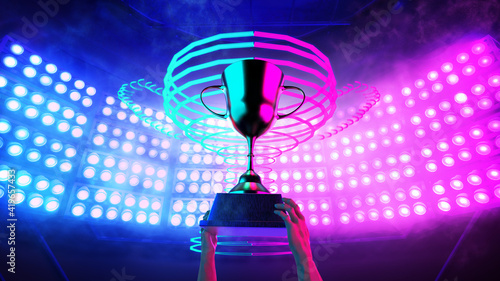 Winner 's hands raise trophy up over the head and background trophy neon light decorate with blue and violet spotlight in the stadium for e-sport winner event.3D rendering photo