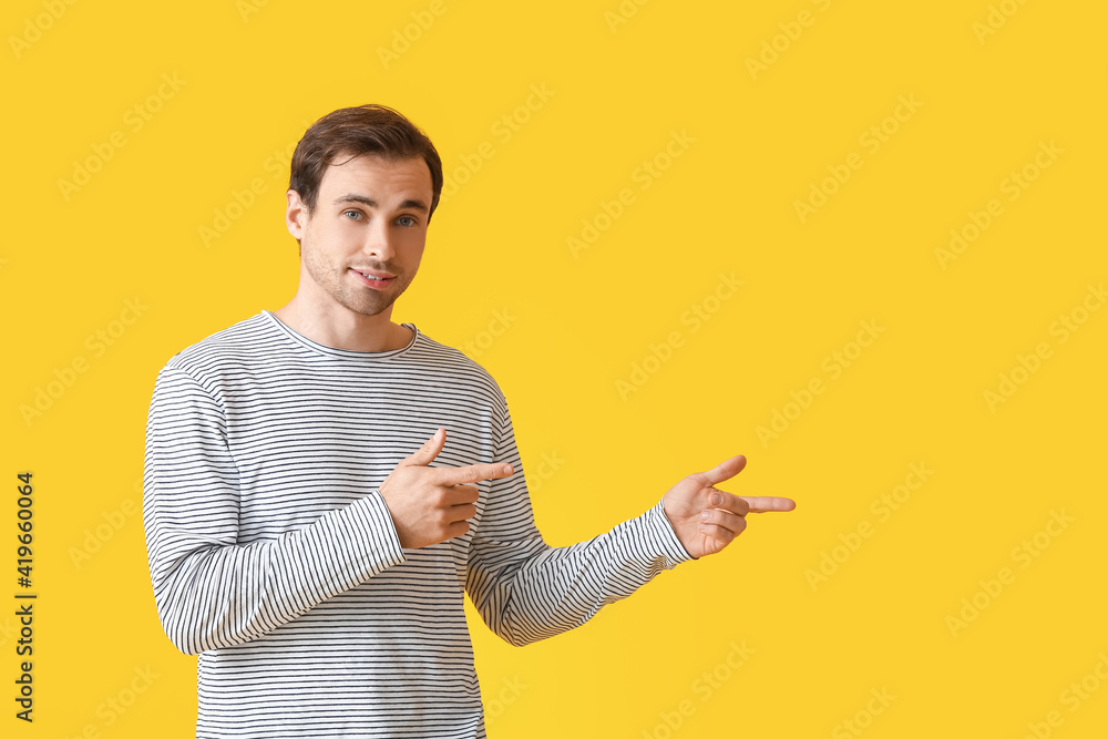 Handsome young man pointing at something on color background Handsome young man pointing at something on color background