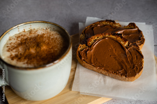 Breakfast of toasts with cocoa cream and cup of coffee with milk and cinnamon