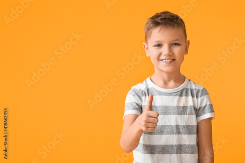 Cute little boy showing thumb-up on color background