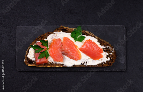 Smoked salmon with cream cheese on black bread. Traditional Danish sandwich. On a gray background. Top view.