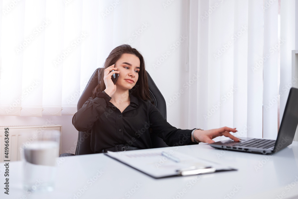 Beautiful young businesswoman working from her office while making a phone call. Beautiful young businesswoman working from her office while making a phone call.