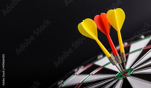 Red and yellow darts arrows on center of dartboard. Concept o business target, success and win.