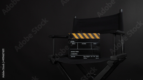 Director chair and Clapper board or movie slate use in video production or film and cinema industry. It's put on black blackground.