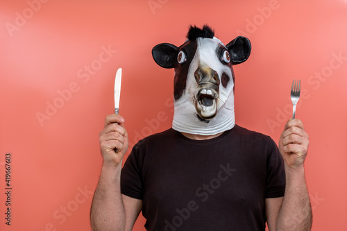 person disguised as a cow showing a knife and fork © rsimona