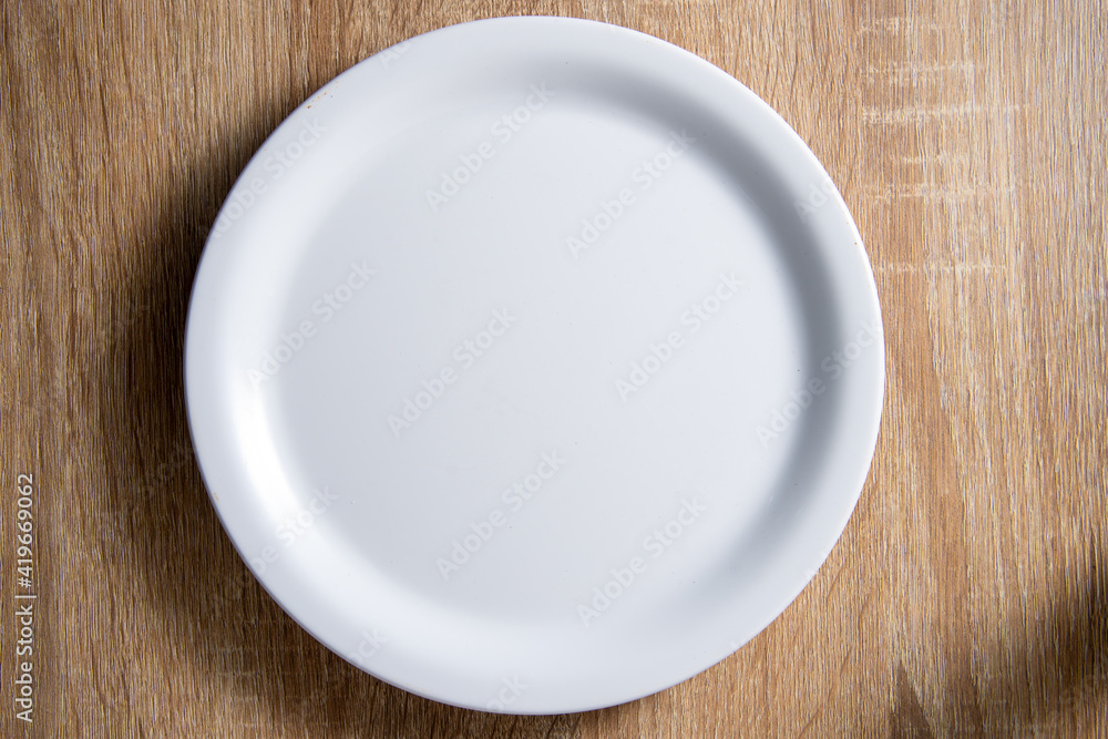 empty white round dish lay on wood table with soft shadow empty white round dish lay on wood table with soft shadow