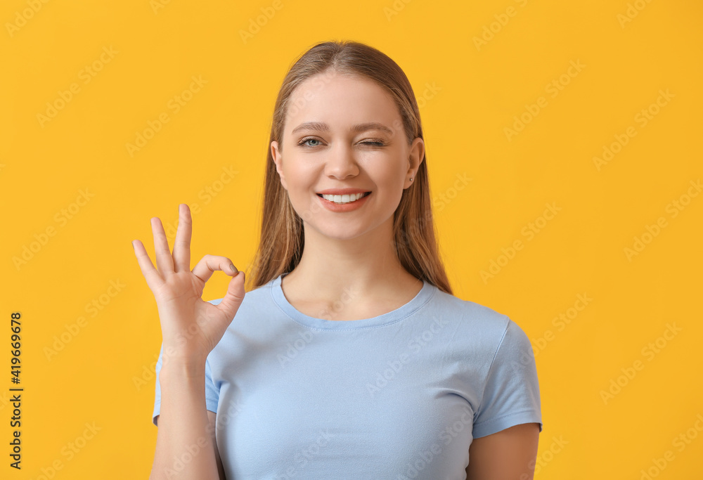 Beautiful smiling young woman showing OK on color background Beautiful smiling young woman showing OK on color background