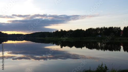 Summer landscape with a lake in the evening. The reflection of the blue sky in the water.