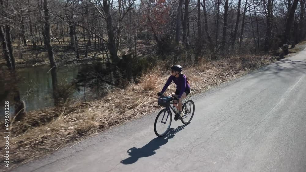 Side view of happy mature woman biking along a river on a beautiful spring day with the sun shining. Side view of happy mature woman biking along a river on a beautiful spring day with the sun shining.