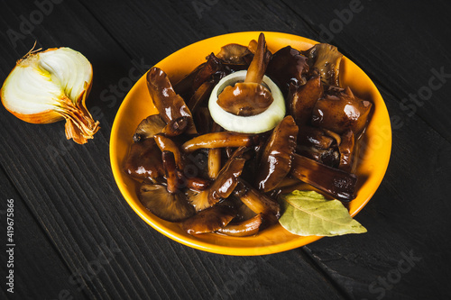 Armillaria mellea or honey fungus marinated in a yellow plate with spices and onions on a vintage table. Idea for a delicious snack for lunch photo