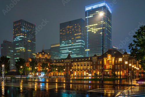 Tokyo train station in from of modern towers at a rainy night in Japan.
