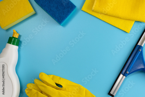 Obraz na płótnie Top view of house cleaning supplies: rubber gloves, sponges, cloths, squeegee and detergent on blue background. Flat lay. Copy space w salonie