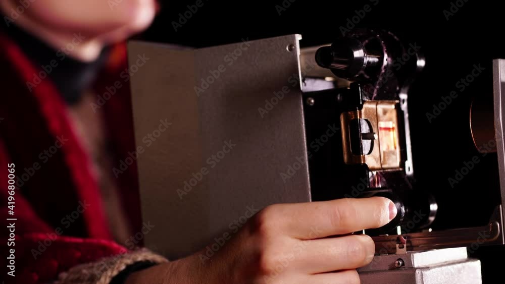 Close-up of an old slide projector and hand spinning a wheel that moves film with pictures. There is a device for showing photo negatives. Vintage retro technology concept. Equipment for entertainment Close-up of an old slide projector and hand spinning a wheel that moves film with pictures. There is a device for showing photo negatives. Vintage retro technology concept. Equipment for entertainment