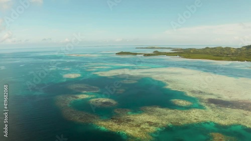 Tropical island covered with forest surrounded by an atoll and a coral reef. Bucas grande, Philippines. Summer and travel vacation concept. photo