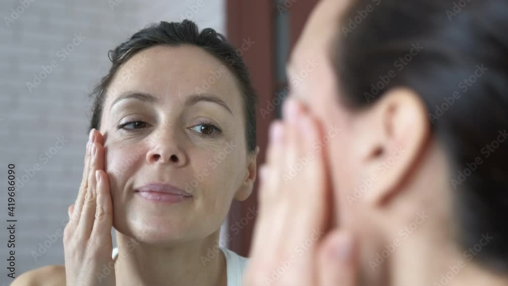 Wrinkles in the mirror. A woman in her forties looks in the mirror at her wrinkles. Wrinkles in the mirror. A woman in her forties looks in the mirror at her wrinkles.