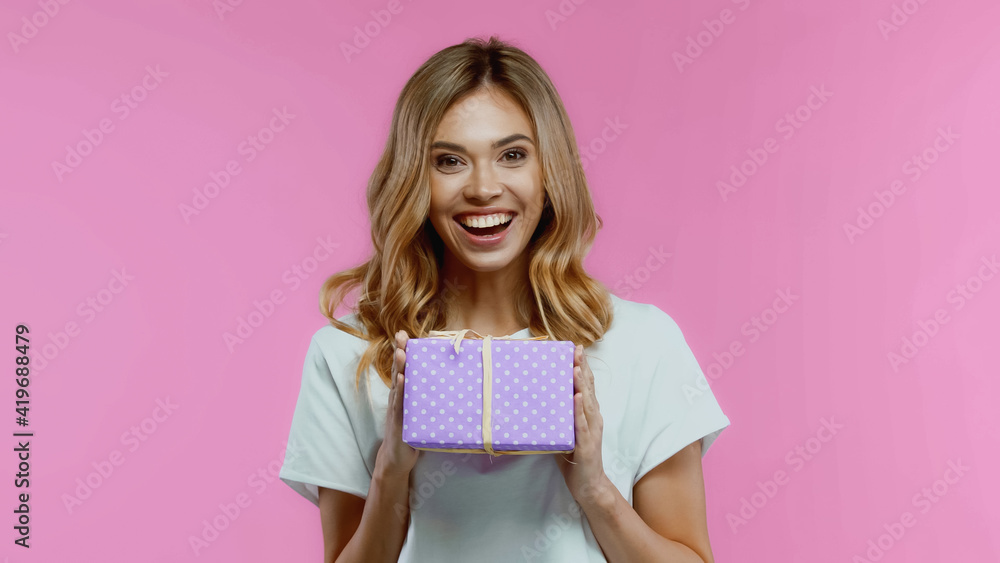 cheerful blonde woman holding gift box isolated on pink cheerful blonde woman holding gift box isolated on pink