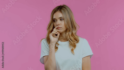 pensive young woman looking away isolated on pink