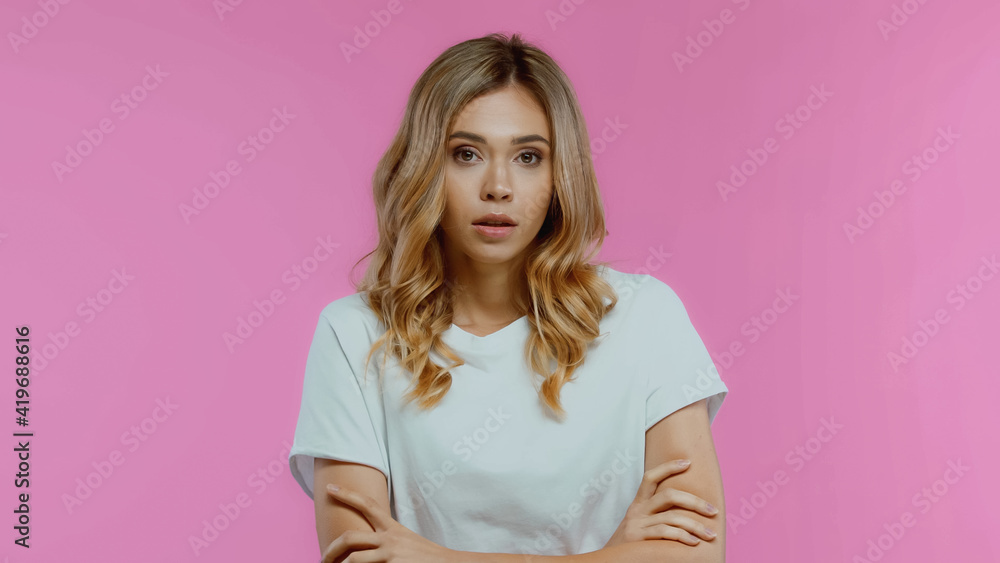 worried and blonde woman with crossed arms isolated on pink worried and blonde woman with crossed arms isolated on pink