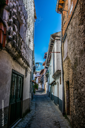 Calle estrecha de una peque  a aldea de monta  a con fachadas de varios tipos  encaladas  de piedra  con tejas  etc.