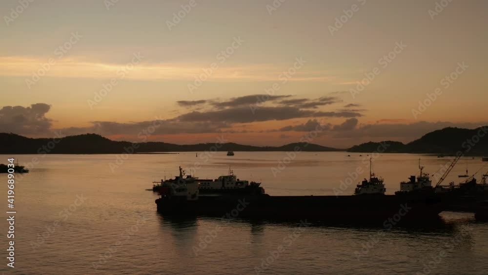 Silhouettes of ships in the seaport during sunset. Sunset in the sea bay. Siargao, Philippines. Dapa Ferry Terminal. Silhouettes of ships in the seaport during sunset. Sunset in the sea bay. Siargao, Philippines. Dapa Ferry Terminal.