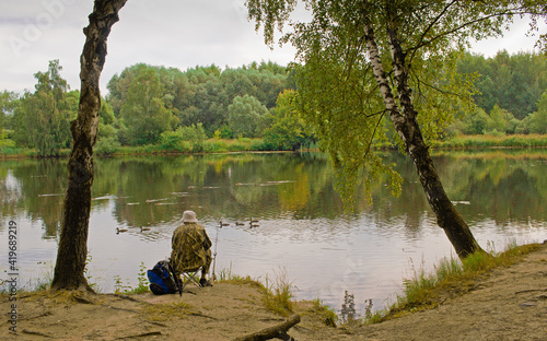 Alone fisherman with a fishing rod on the shore of the lake