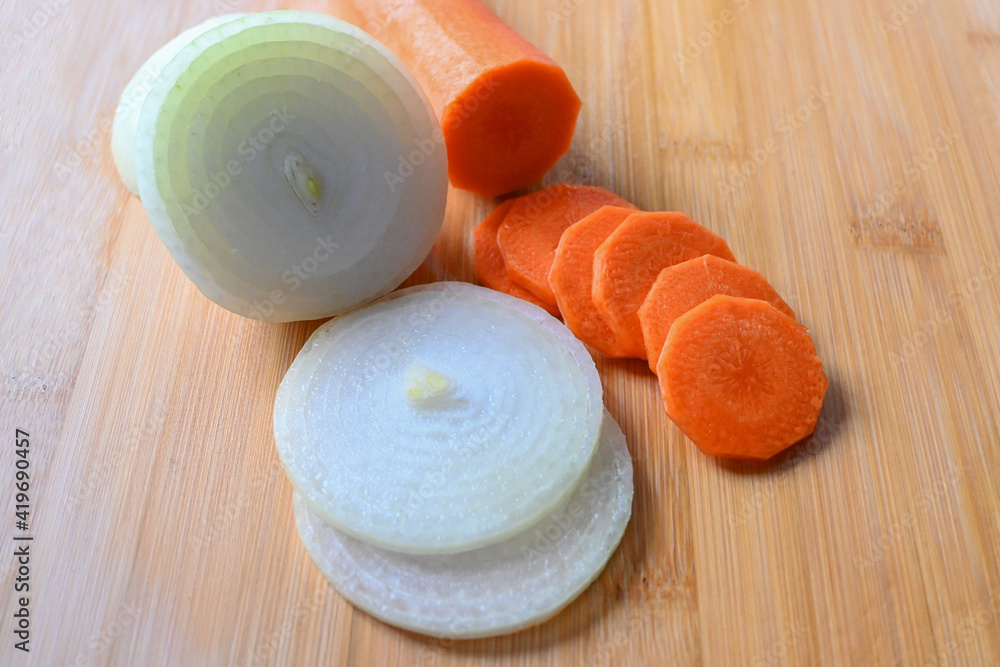 Onions and carrots cut into small circles on a cutting board for cooking. Onions and carrots cut into small circles on a cutting board for cooking.