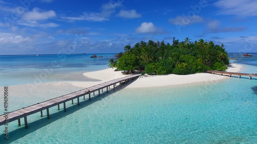 Tropical island in Maldives, aerial panoramic view. Beautiful paradise island with white sand, coco palm trees and crystal clear turquoise water. Maldives, Seychelles, Bora Bora, French Polynesia.