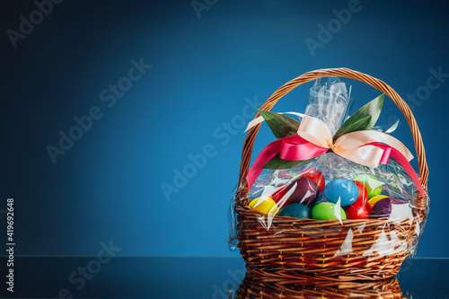 Canvas Print Easter gift basket with multicolor eggs, blue background with copy-space