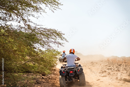 People quad biking across desert terrain