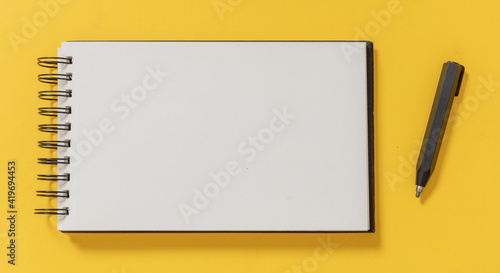 Foto Blank notepad and architect engineer pencil on yellow color background, top view