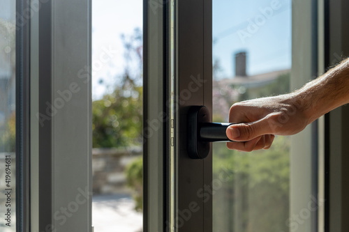 Aluminum window frame detail. Male hand opens the metal door closeup view.