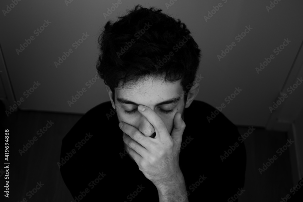 Teenager portrait sadness takes his head in his hands black and white