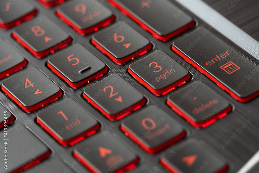 Black keys with red backlights on gaming laptop keyboard. Focused on numeric buttons. Black keys with red backlights on gaming laptop keyboard. Focused on numeric buttons.