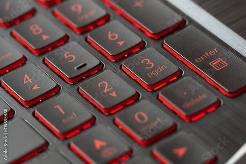 Fotografie Black keys with red backlights on gaming laptop keyboard