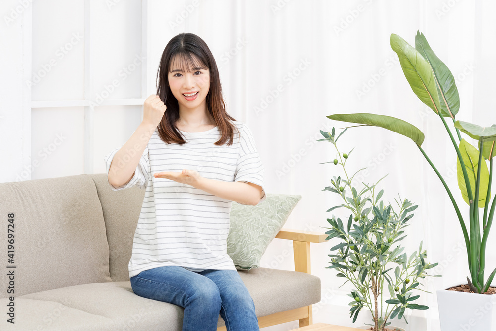部屋のソファに座って納得のジェスチャーをする若い女性 部屋のソファに座って納得のジェスチャーをする若い女性