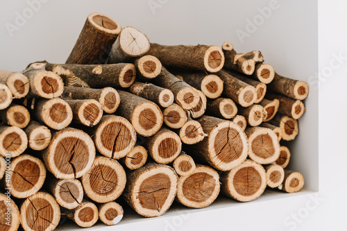 Chopped stacked firewood on a shelf in white wall. 