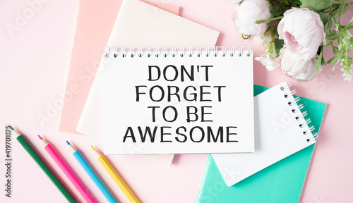 Word quotes of DON'T FORGET TO BE AWESOME on colorful memo papers with wooden background.