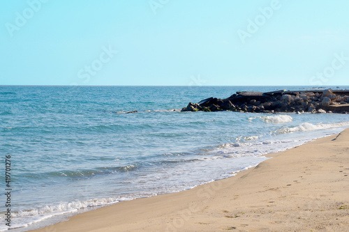 empty sandy beach, big stones on the shore, sea horizon and clear sky
