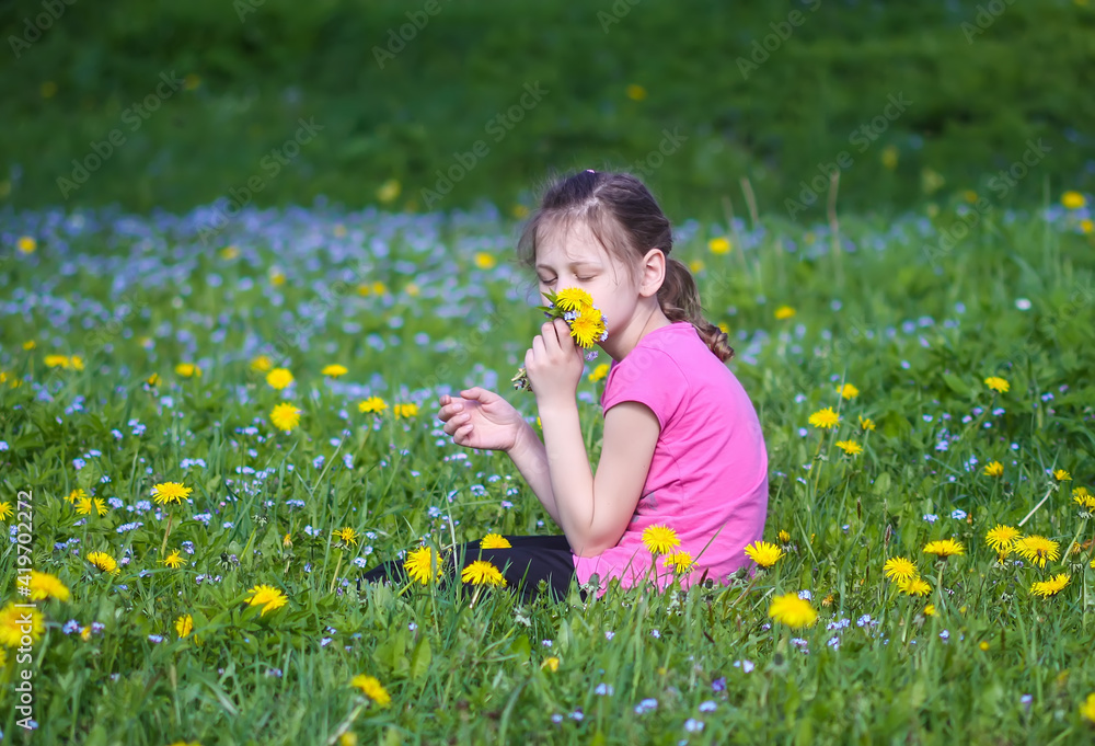 A girl on the green spring meadow with a lot of wildflowers in sunlight. Child exploring nature. A girl on the green spring meadow with a lot of wildflowers in sunlight. Child exploring nature.