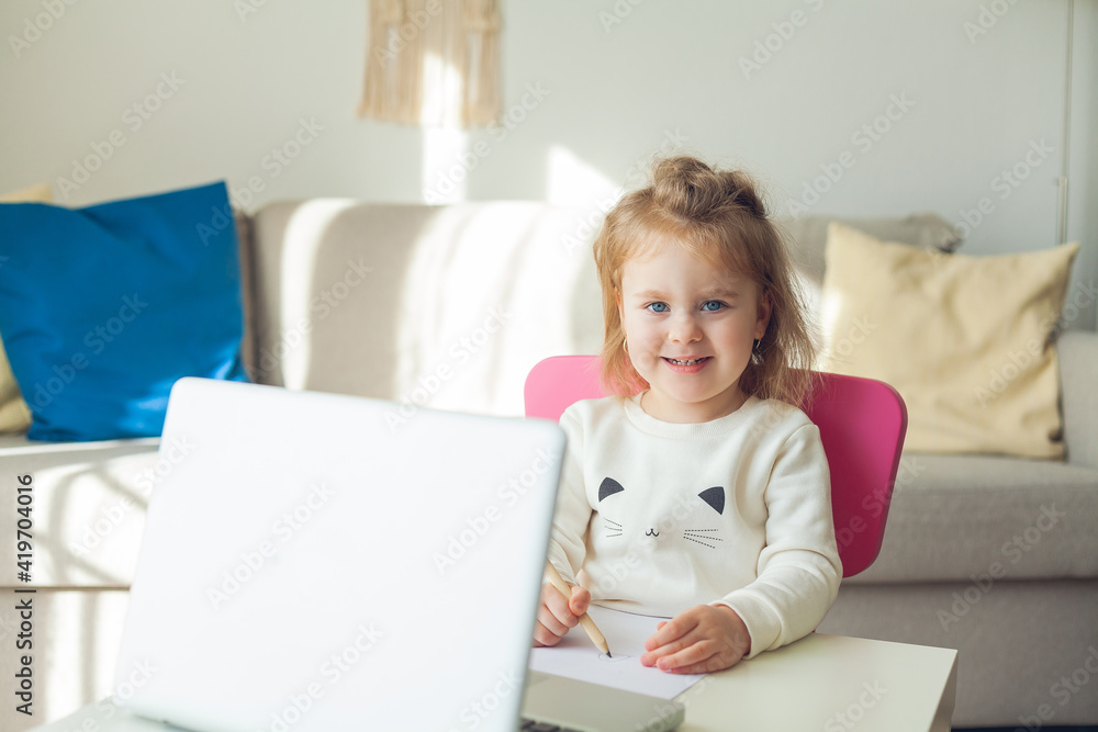 A little girl of 3 years old is studying online. The little girl draws. Quarantine. A little girl of 3 years old is studying online. The little girl draws. Quarantine.