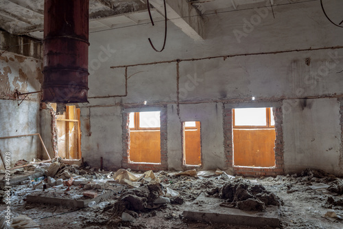 A large rusty pipe sticks out of the ceiling in the ruins of a former